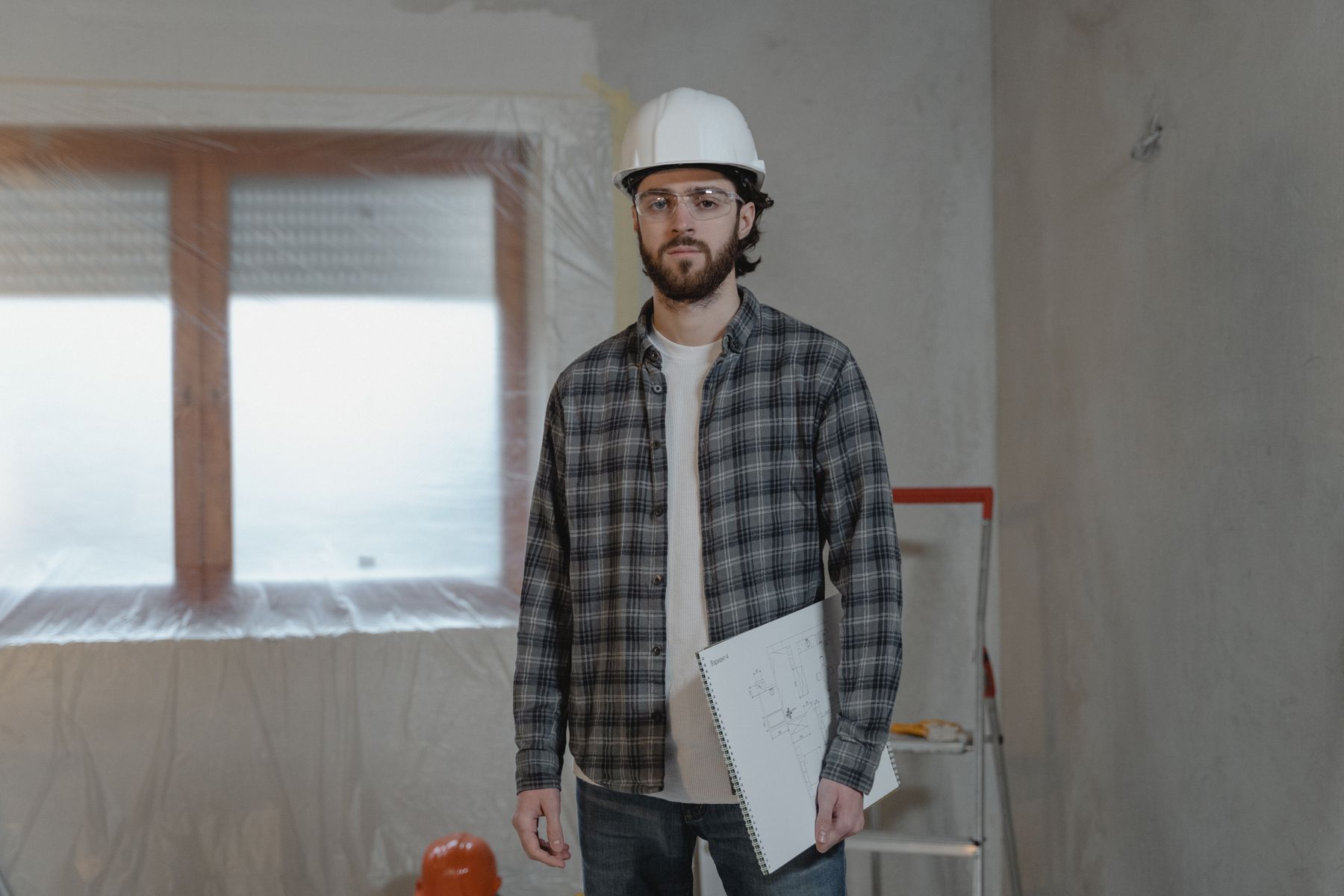 artisan sur un chantier de rénovation consultant les plans avant de démarrer les travaux