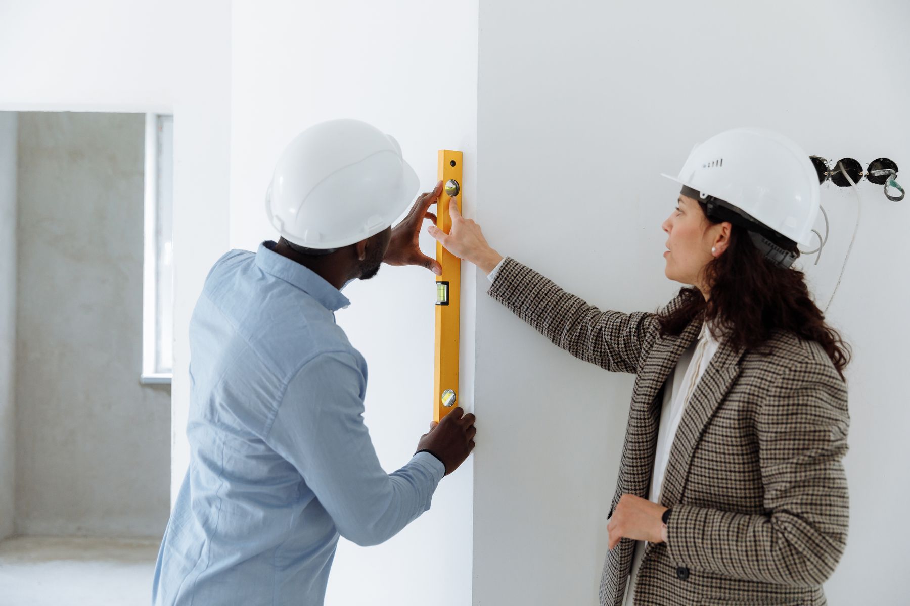 deux artisans vérifient l’alignement d’un mur avec un niveau avant de poursuivre le chantier