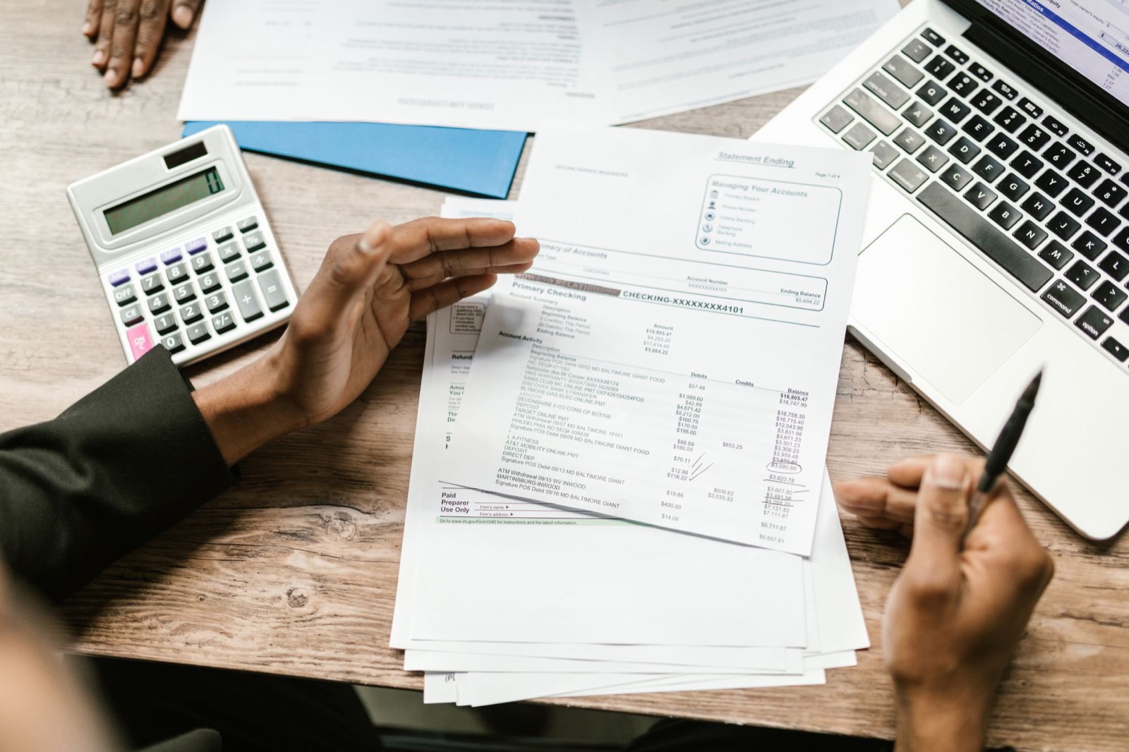 Relevé bancaire, calculatrice et tickets de caisse posés sur un bureau pour pointer les dépenses d'un logement loué